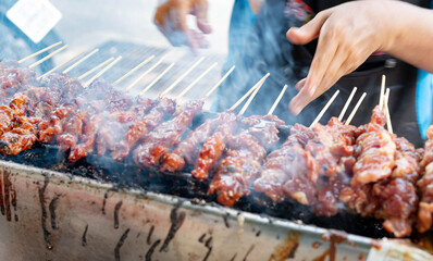 The delicious bbq porks grilling on open grill, outdoor kitchen, tasty food roasting on charcoal oven with the dipping Thai style