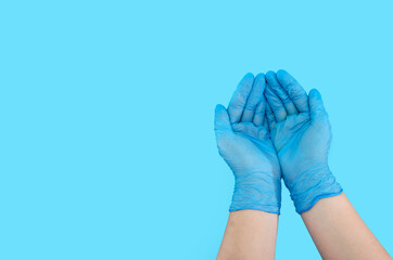Human hands in blue surgical gloves, gesture. Isolated on a blue background. Palms in latex gloves. Copy of space. Place for an inscription.