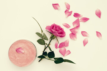 Jar with a homemade moisturizing beauty cream and pink rose flower.  Top view.