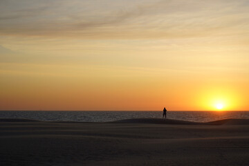 Fototapeta na wymiar Person watching a beautiful sunset at the beach in Koksijde on a summer day