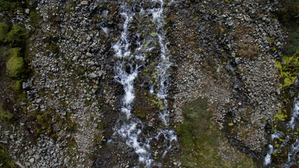 Overhead aerial view of a fresh water stream flowing downhill in the mountains.