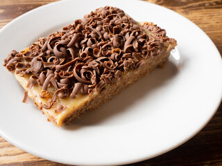 a piece of caramel cake with chocolate curls chocolate shaving topping on white plate homemade cake copy space