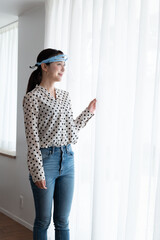 フェイスシールドをしながら窓辺にたっている女性