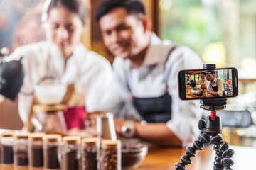 Mobile phone taking Video to two Asian Barista presenting a cup of coffee and dripping coffee show to audience in coffee shop