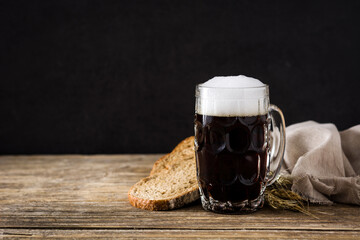 Traditional kvass beer mug with rye bread on wooden table. Copy space