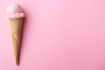 Close up strawberry ice cream in waffles cone against pink background. Copy space.