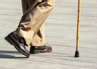 elderly person walking with the help of a stick with a rubber tip - obrazy, fototapety, plakaty
