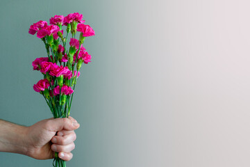Male hand holding flowers on a gradient background