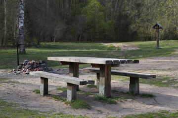 Wooden picnic table and bench. Picnic place in forest with tables and benches on a walking path. Fireplace. 