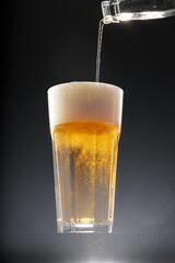 Beer pouring into glass on black background
