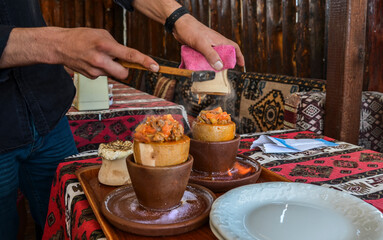 National Turkish dish cooked in a clay pot over fire that is broken before being consumed called...