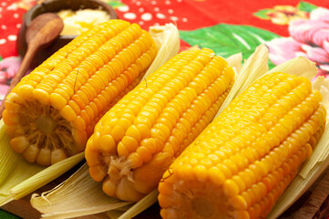 cooked corn with butter on wooden board and colorful table