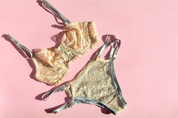 On a pink background, women's underwear is beige with lace. copy space