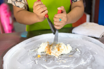 process of making fried ice-cream. Thailand stir-fried ice cream rolls at freeze pan. Organic, natural rolled ice cream, hand made dessert. Fried ice cream machine with steel chilled pan.