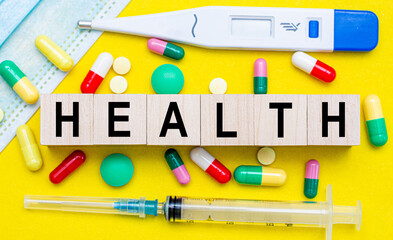 HEALTH - text on cubes. Drug, tablets, thermometer, medical mask on a yellow background. medical concept