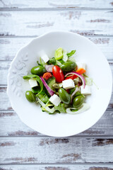 Salad with Green Olives, Cucumber Cherry Tomatoes and Feta Cheese on bright wooden Background. Healthy Snack Idea. Top view. Copy space. 