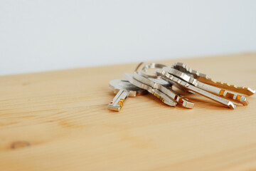 Bunch of keys on a shaped keychain at wooden table background. Concept for real estate or renting home with copy space,Close up.
