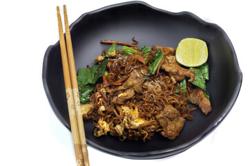 Fried noodles with black soy sauce on a black plate