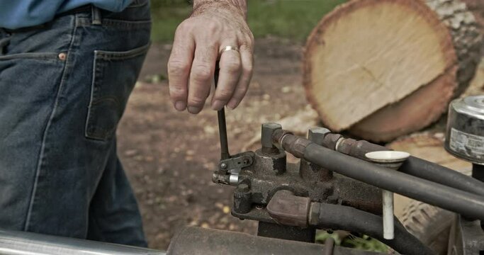 Close up man hand working pneumatic lever control on hydraulic wood splitter - with audio