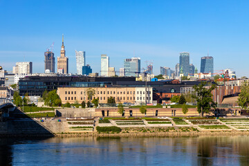 Obraz premium Panoramic view of Srodmiescie city center quarter and Powisle district at Wybrzeze Kosciuszkowskie embankment over Vistula river in Warsaw, Poland
