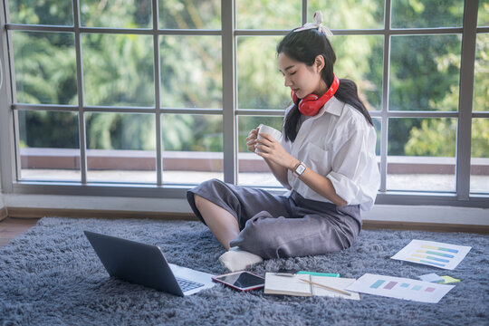 Top View Of Young Asian Woman Working With Laptop Computer In The Living Room. Work From Home And Study At Home Concept.