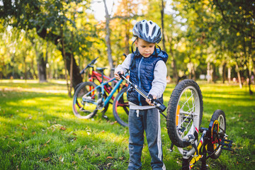 Cyclist boy Bike repair. little boy fixing his bike. Children mechanics, bicycle repair profession. Learning about cycles and engines. Little repairman fix cycle outside in park sunny weather