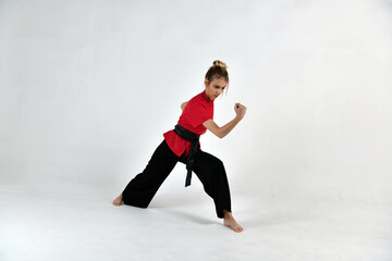 beautiful girl in black and red does exercises for mastery of martial arts