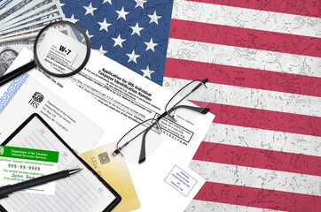 IRS form W-7 Application for IRS individual taxpayer identification number lies on flat lay office...