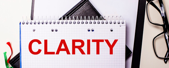 The word CLARITY is written in red in a diary on a light table. Business concept