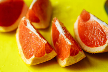 Fototapeta na wymiar slices of juicy red grapefruit on a bright yellow board