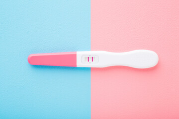 Pregnancy test with two stripes on light pink blue table background. Pastel color. Positive result....