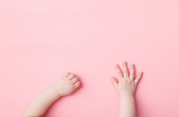 Baby girl hands on light pink table background. Pastel color. Closeup. Point of view shot. Top down...