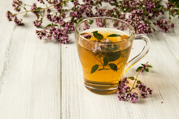 Medicinal drink of oregano in a glass Cup on a wooden table. 