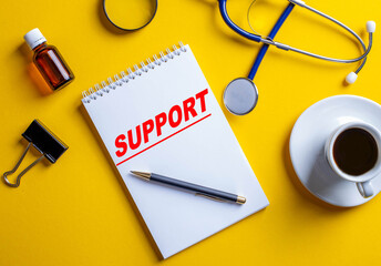 The support service is written in red font on a sheet of paper that lies on a yellow background near a stethoscope, coffee and pen