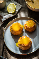 Shaped mini bundt cakes filled with lemon curd on old wooden table.