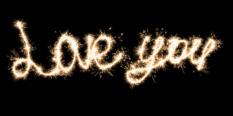 The inscription Love you on a black background with sparklers using a simulated long exposure.