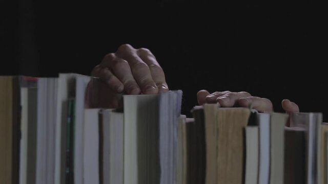 Manos agarrando libros en biblioteca con fondo negro
