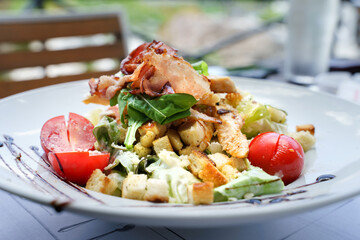 Cesar salad in white plate on the table at restaurant in day