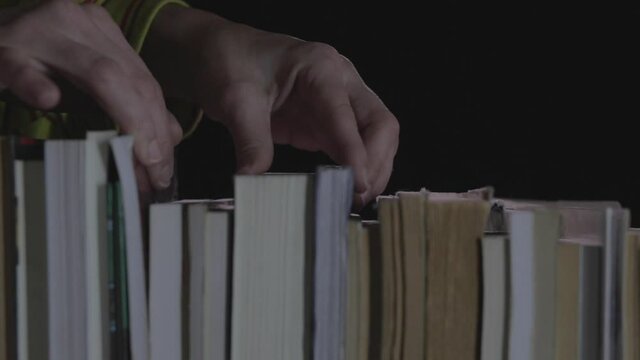 Manos de mujer buscan libro en biblioteca