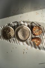 Homemade oatmeal cookies and bowls with ingredients on white kitchen table.