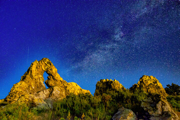 Rocky ridge of a mountain (rock formation called The Ring, or "Halkata") in Sliven, Bulgaria, against a brilliant starry sky