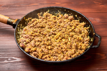 Grilled minced meat with onions, spices and cream in a pan on a dark wooden background. Cooking toppings.