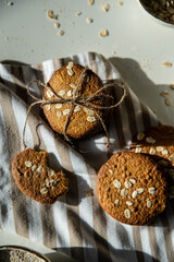 Homemade oatmeal cookies and bowls with ingredients on white kitchen table.