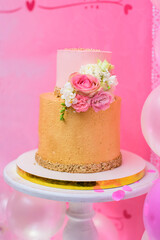 Two-tiered golden birthday cake decorated with  flowers.