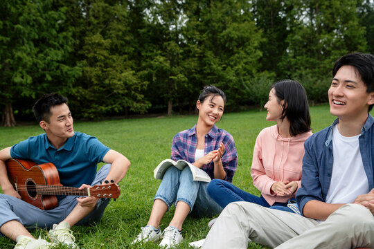 Happiness of college students play the guitar singing on the grass