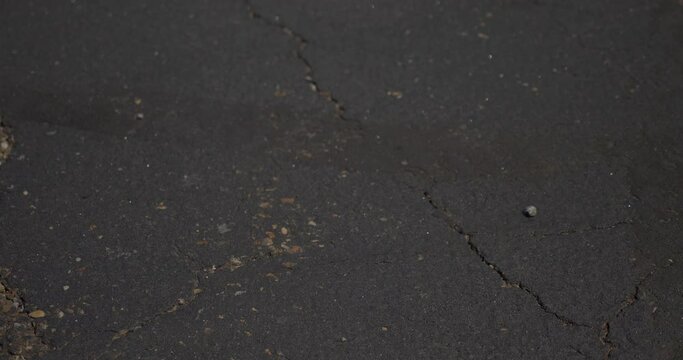 A closeup view of a used surgical mask being picked up in a store's parking lot. Shot at 48fps slow motion.  	