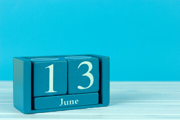 wooden calendar with the date of June 13 on a blue wooden background, International Albinism...