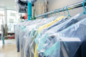 Clean clothes on hangers in the laundry room protected with plastic