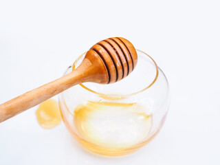 Top view of honey stick in empty honey glass jar with stain of honey isolated on white background.