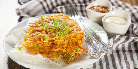 Hash browns grated potatoes cutlets in a plate on a table, selective focus